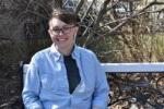 student sitting on a bench with tree branches in background