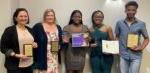 5 people smiling at camera and holding awards