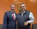 2 men smiling at camera with one holding excellence challenge coin