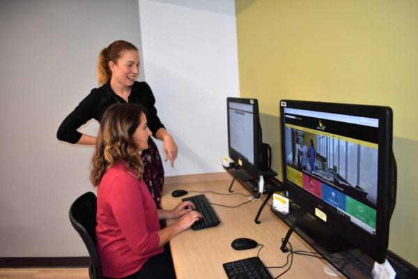 Financial Aid director helping a student sitting at a computer